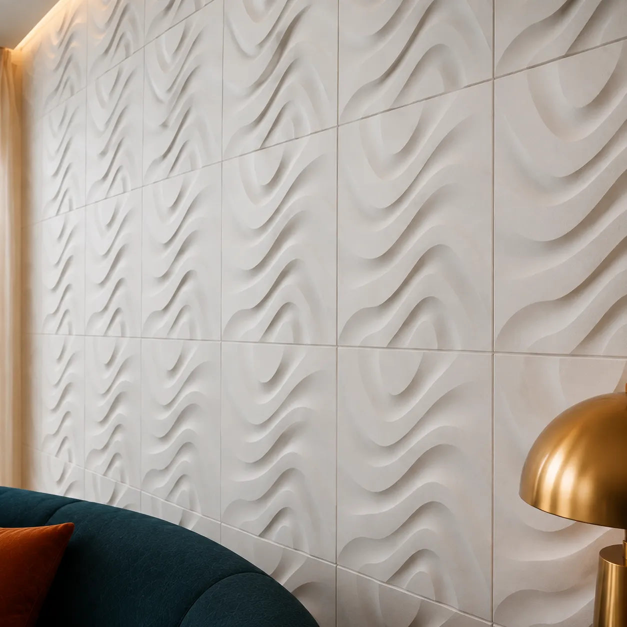 Close-up angled view of white 3D gypsum wall panels showing their flowing relief, precise square joints, and matte textured surface beside a blue sofa and brass lamp