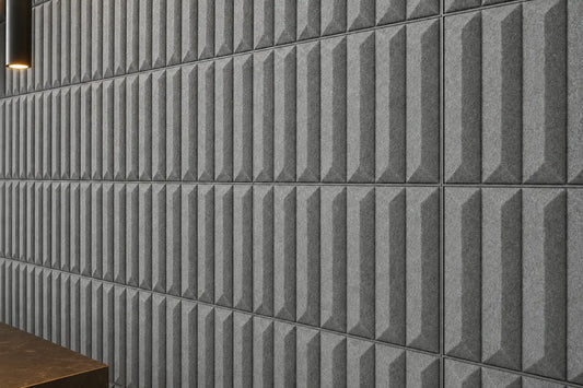 Close-up of grey GROVE 3D acoustic felt wall panels showing the geometric relief, regular seams and textured felt surface