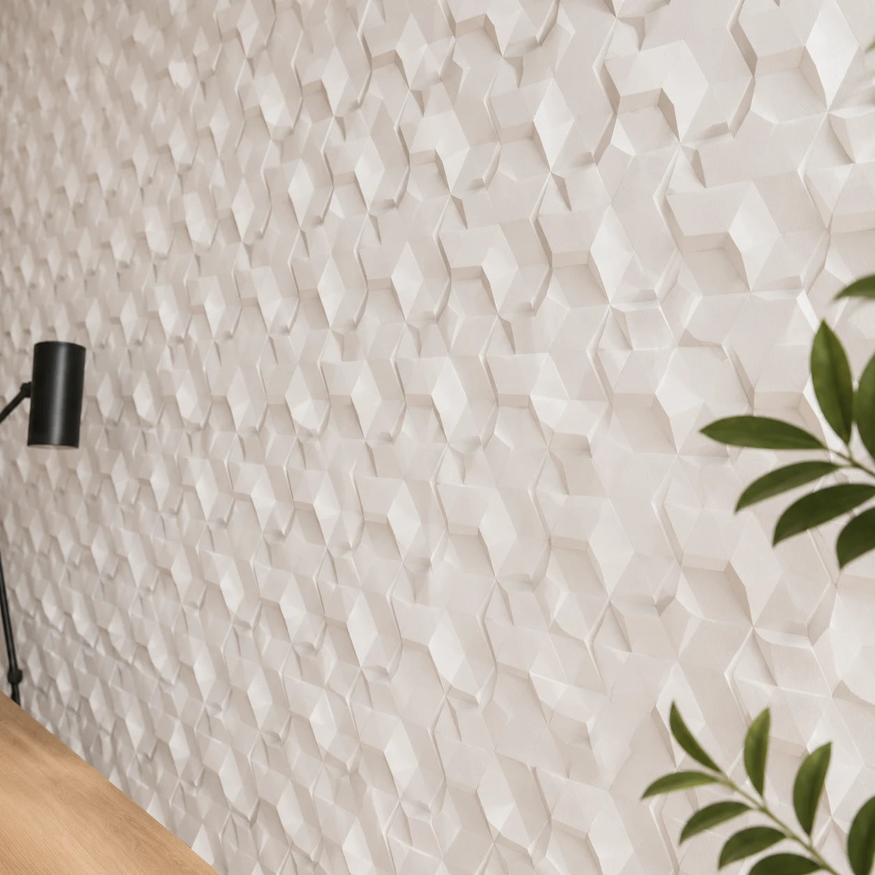 Close-up angled view of white 3D polystyrene wall panels, highlighting their irregular faceted hexagonal relief, crisp edges, and dimensional shadows