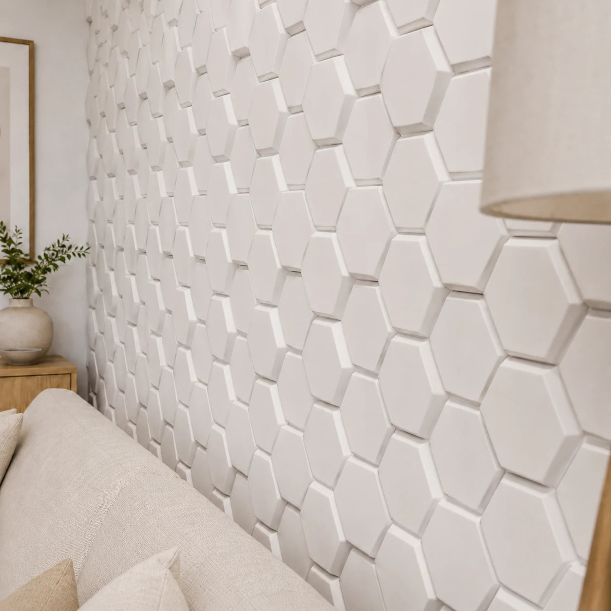 Close-up angled view of white 3D polystyrene wall panels, highlighting their raised honeycomb pattern, beveled edges, and dimensional shadows