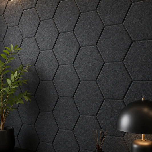 Dark black hexagonal acoustic wall panels mounted on a wall, styled with a green potted plant on the left and a black dome table lamp on the right.