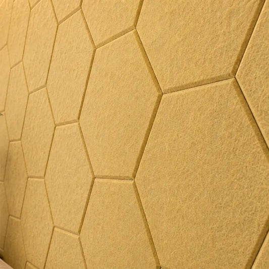 Yellow HEXA 3D felt PET wall panels in a stylish living room with a cream sofa, leather armchairs and warm wooden furniture cloes up view