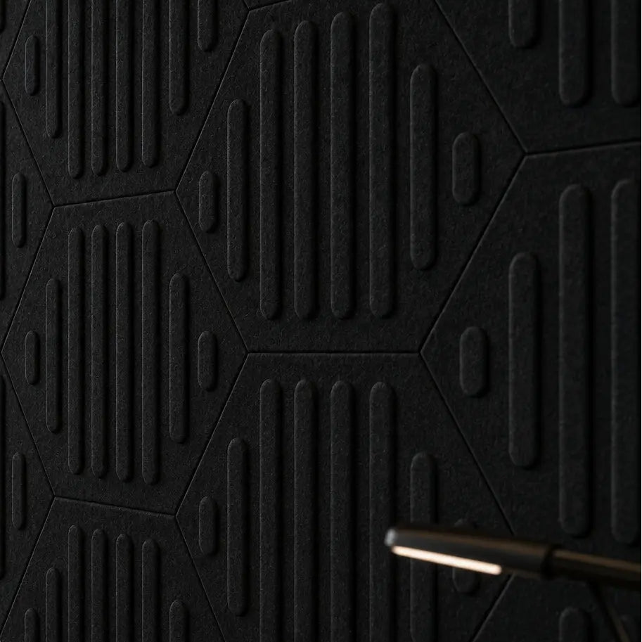 Close-up of black HEXA RIFT 3D felt wall panels showing the geometric layout, raised relief and fibrous texture