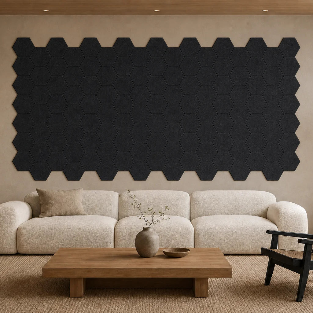 Large installation of flat black hexagonal felt acoustic panels above a cream sofa in a modern living room.
