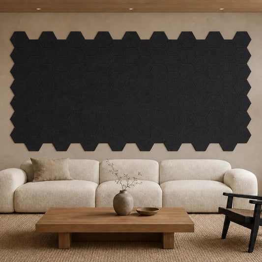 Large installation of flat black hexagonal felt acoustic panels above a cream sofa in a modern living room.
