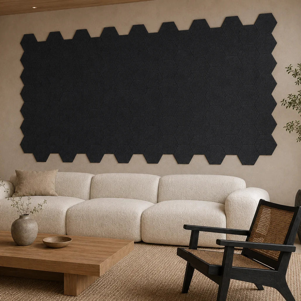 Angled view of flat black hexagonal acoustic panels covering the wall behind a cream sofa