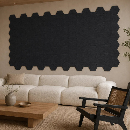 Angled view of flat black hexagonal acoustic panels covering the wall behind a cream sofa
