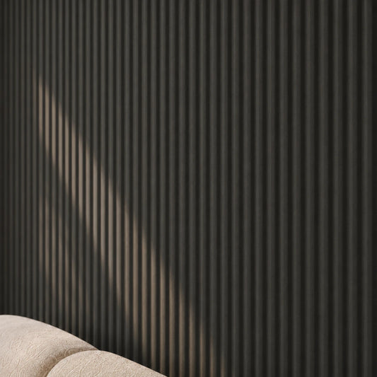 Close-up of black matte concave fluted wall panels with narrow vertical grooves, shown behind the corner of a cream upholstered sofa.