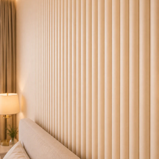 Close-up angled view of beige fluted wall panels, highlighting their rounded raised profile, regular spacing, subtle texture, and warm illumination, with part of the bed and bedside lamp visible for scale