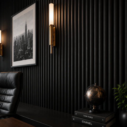 Close-up of matte black fluted wall panels with rounded raised profiles, complemented by a brass wall light, framed black-and-white city artwork, a decorative globe, books, and a green plant