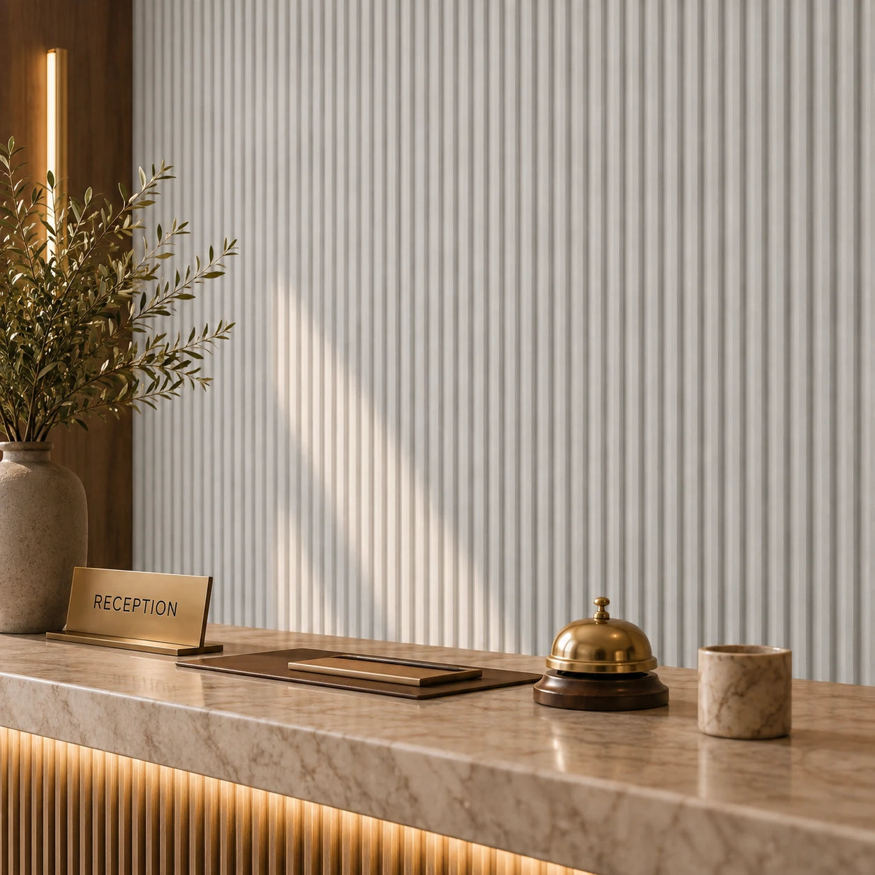 Close-up of a luxury hotel reception desk with a brass bell, reception sign and cashmere fluted wall panels in the background