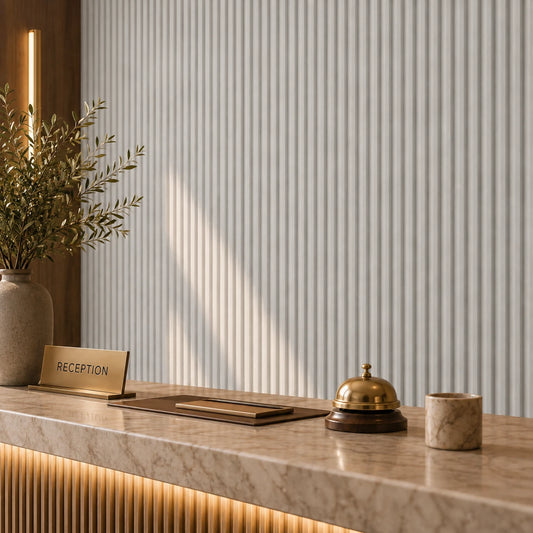 Close-up of a luxury hotel reception desk with a brass bell, reception sign and cashmere fluted wall panels in the background