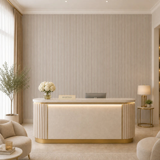 Front view of an elegant hotel reception with a curved cream-and-gold desk, cashmere fluted wall panels, neutral seating, floral décor, and warm ambient lighting
