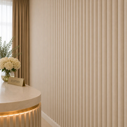 Close-up angled view of cashmere fluted wall panels, showing their narrow rounded relief and subtle texture, with part of the reception desk, a flower arrangement, and a gold reception sign