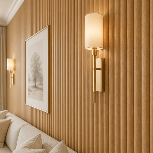 Close-up angled view of narrow, rounded natural oak wall panels, showing their convex profile, wood grain, and vertical rhythm, with a brass wall lamp, framed artwork, and part of a cream sofa