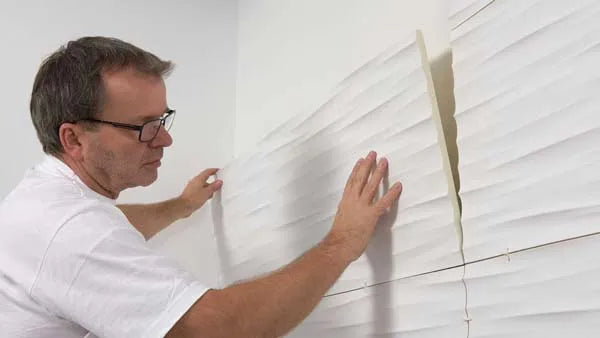 Man installing white NMC paneling on a wall step 4