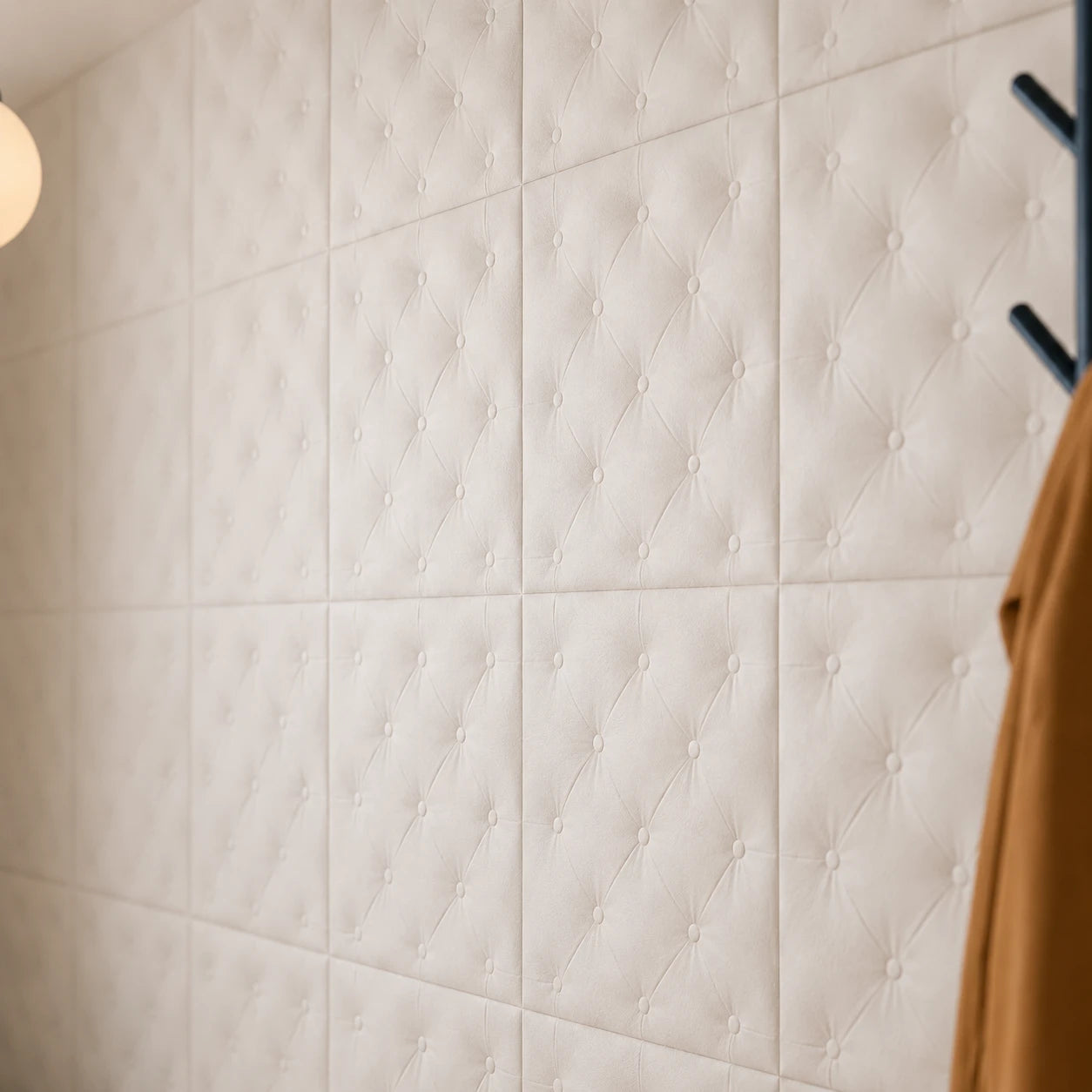 Close-up angled view of white 3D polystyrene wall panels, highlighting their padded-look diamond tufting, decorative buttons, soft texture, and subtle relief