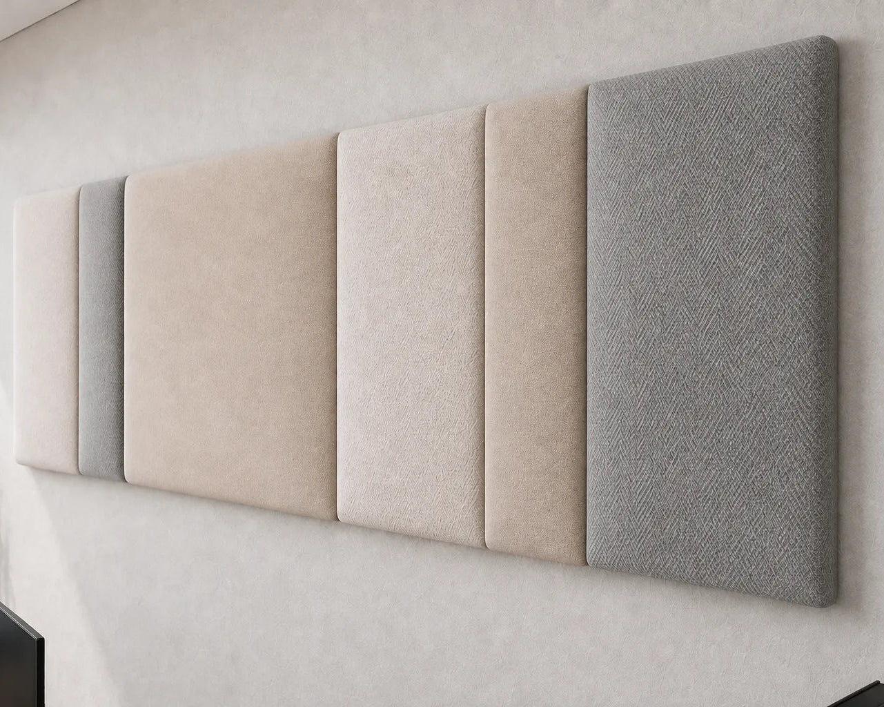 Close-up angled view of a multi-section upholstered wall panel, highlighting its varied panel widths, padded relief and contrasting woven fabric textures