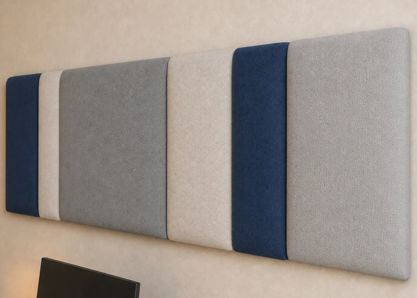 Close-up angled view of a multi-section upholstered wall panel, highlighting its varied widths, padded relief and contrasting navy, grey and cream fabric textures
