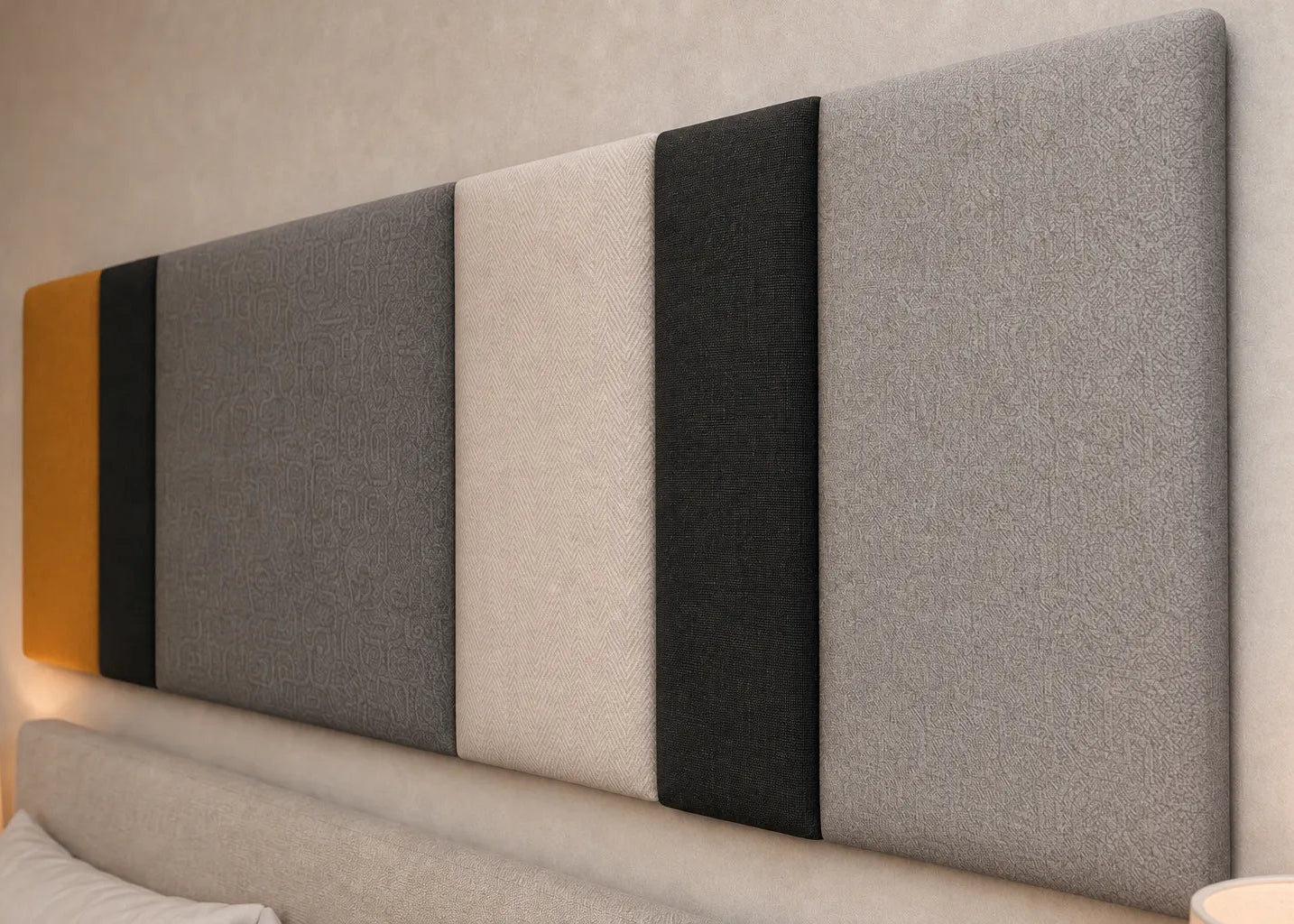 Close-up angled view of a multi-section upholstered wall panel, highlighting its mustard, black, charcoal and cream colours, varied widths and contrasting fabric textures