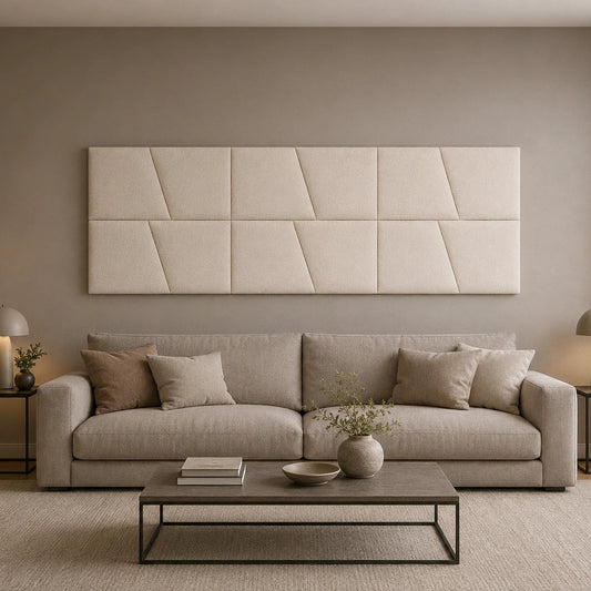 Front view of a large cream upholstered wall panel with geometric diagonal seams, displayed above a neutral sofa in a modern living room