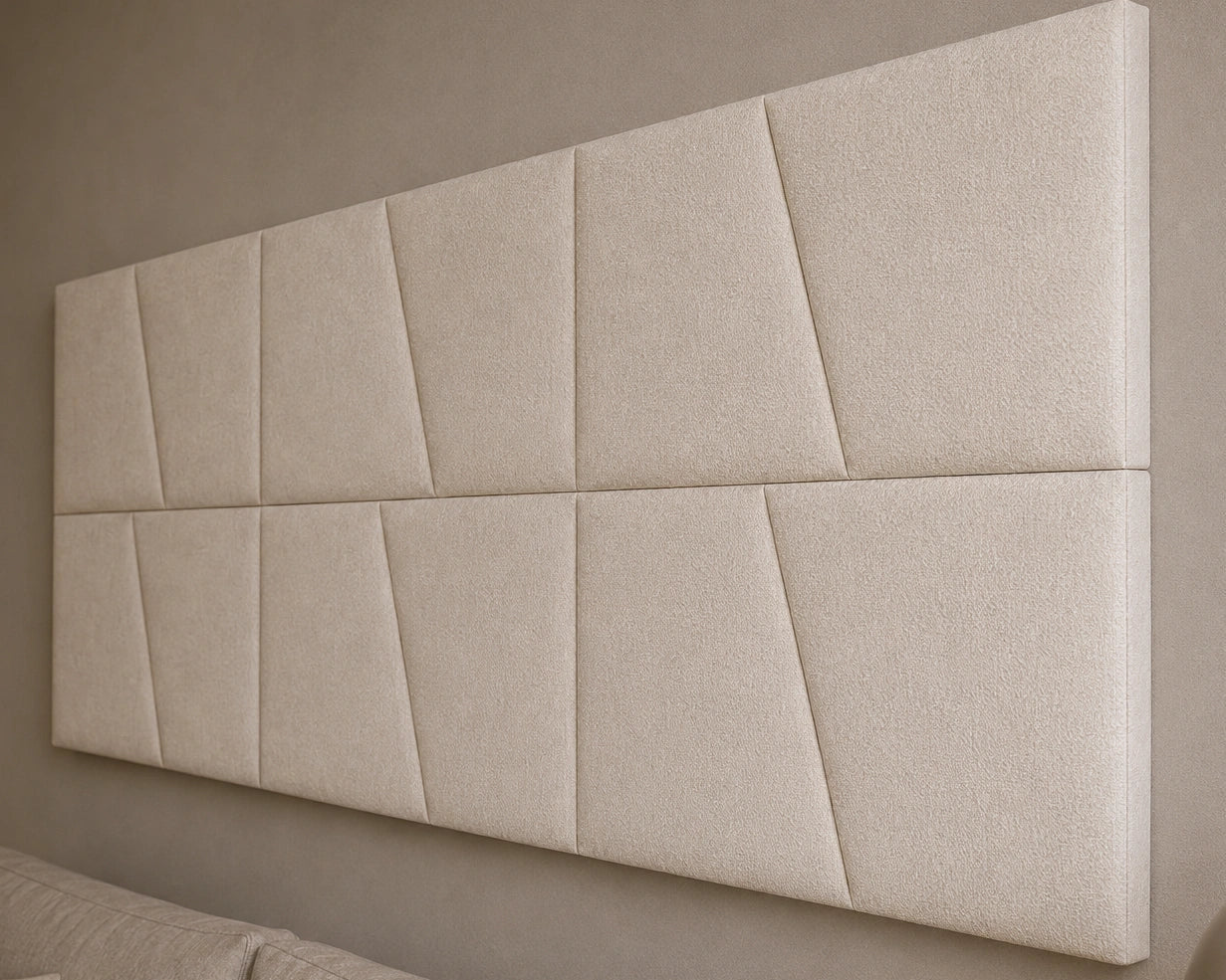 Close-up angled view of cream upholstered wall panels, highlighting their diagonal seams, padded relief, precise joints and textured fabric finish