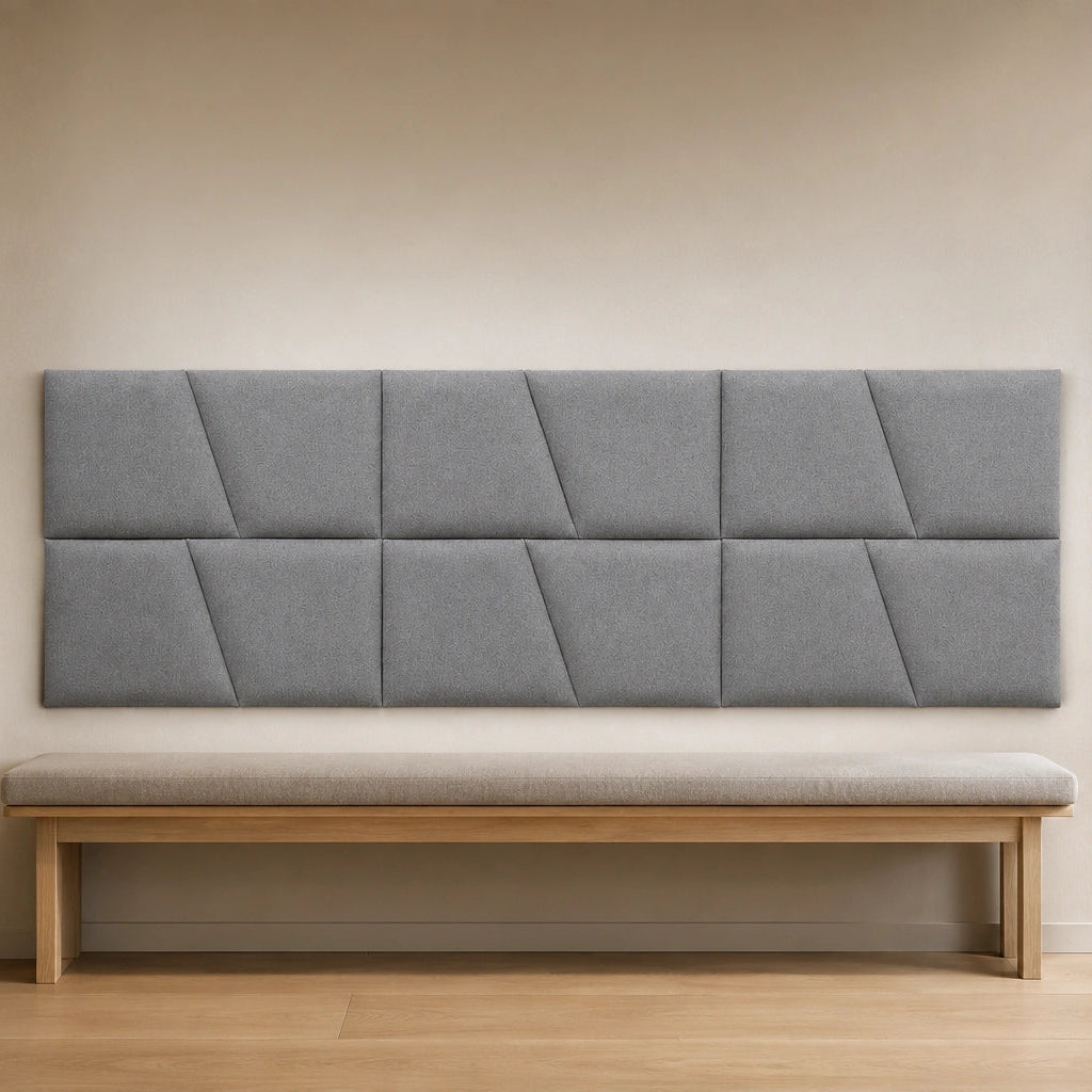 Front view of a large cream upholstered wall panel with geometric diagonal seams, displayed above a neutral sofa in a modern living room