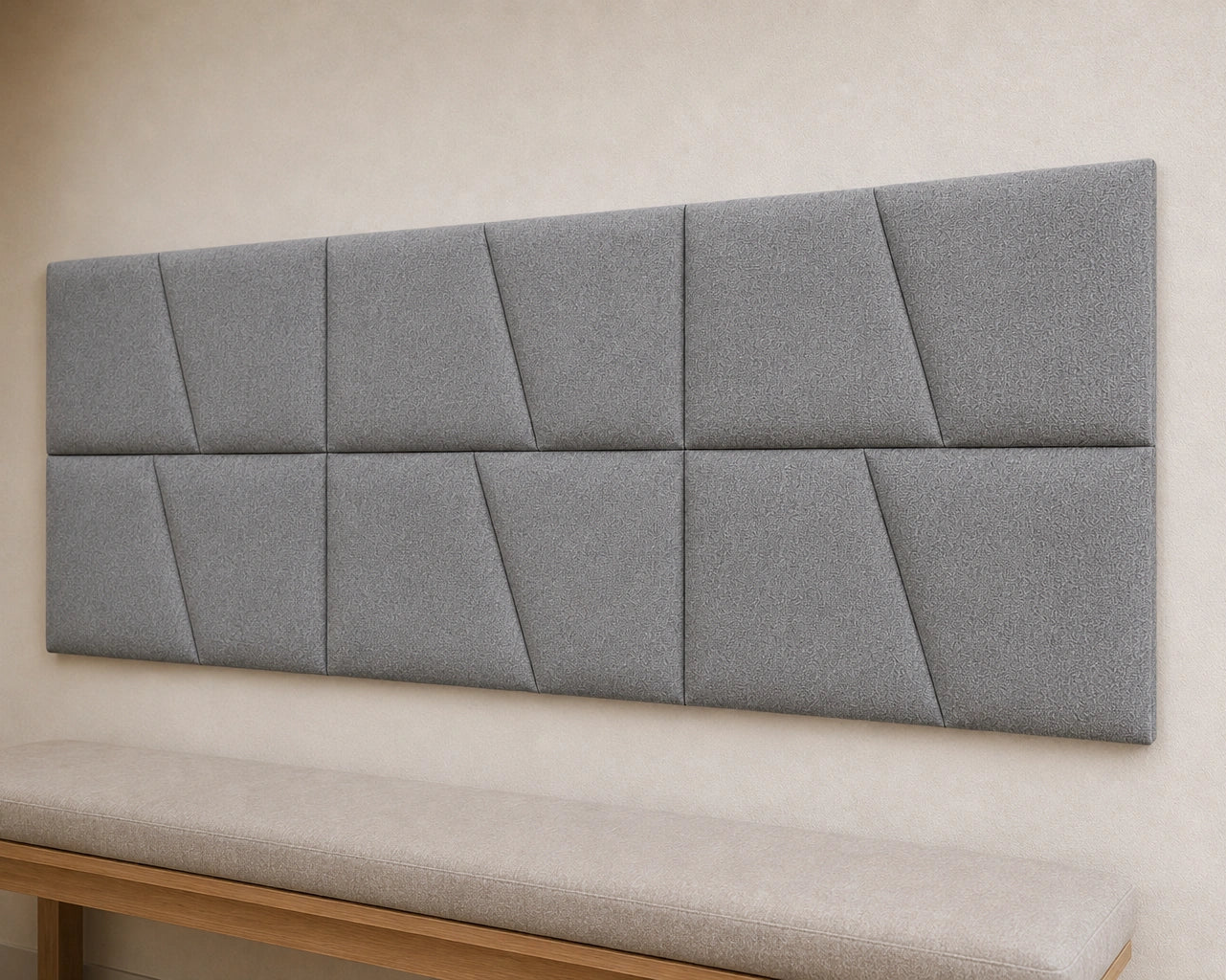 Close-up angled view of cream upholstered wall panels, highlighting their diagonal seams, padded relief, precise joints and textured fabric finish
