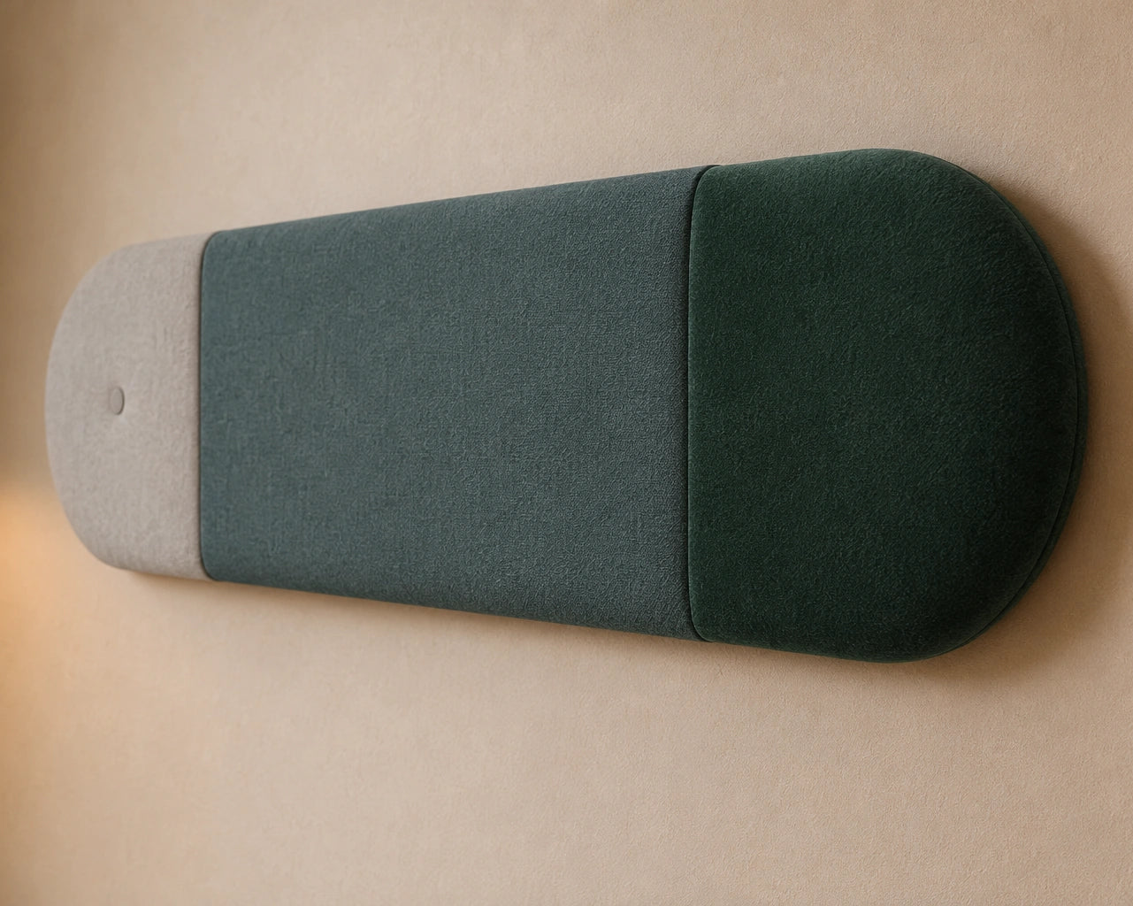 Close-up angled view of a three-section upholstered wall panel, highlighting its light grey and green colours, rounded relief, seams and textured fabric finish