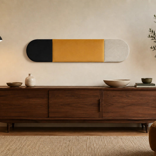Front view of a three-section black, mustard and cream upholstered wall panel displayed above a dark wooden sideboard in a warm living room