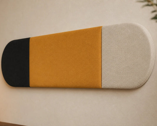 Close-up angled view of a three-section upholstered wall panel, highlighting its black and mustard fabrics, textured cream end, rounded shape and vertical seams