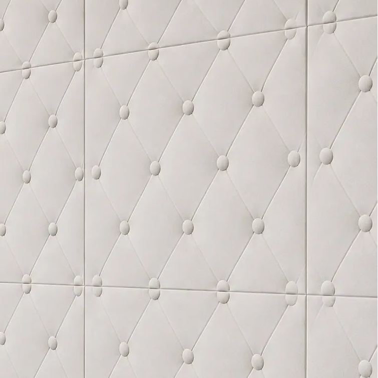 Close-up angled view of white gypsum 3D wall panels with a button-tufted diamond pattern, installed above a dark wooden cabinet in warm natural light