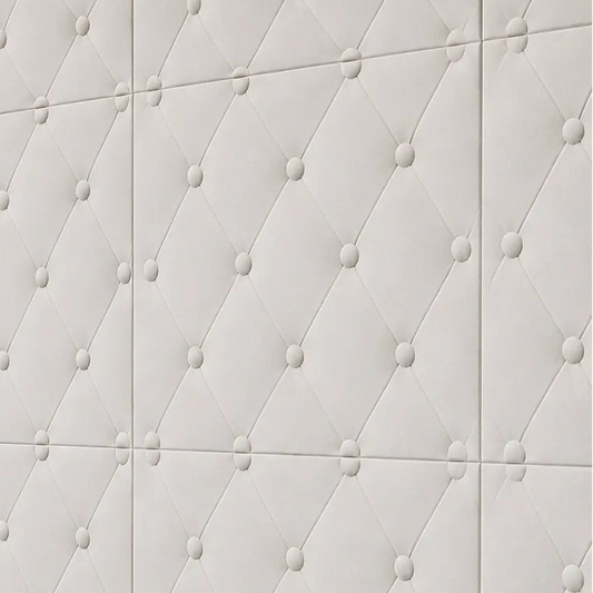 Close-up angled view of white gypsum 3D wall panels with a button-tufted diamond pattern, installed above a dark wooden cabinet in warm natural light
