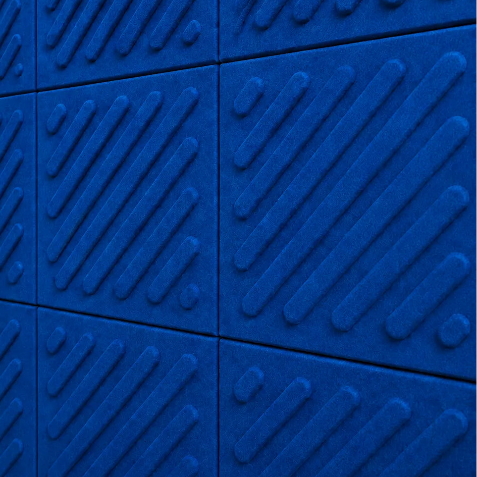 Close-up of indigo acoustic felt wall panels highlighting the fibrous texture, raised relief and module connections