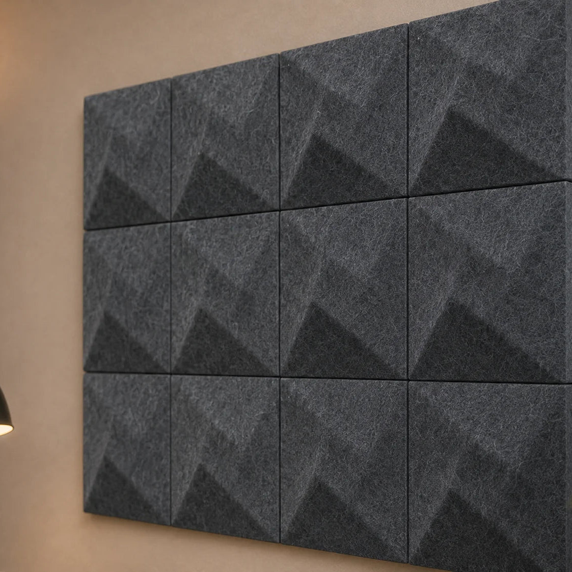 Close-up of grey 3D acoustic panels highlighting their geometric relief, regular seams and fibrous PET felt texture