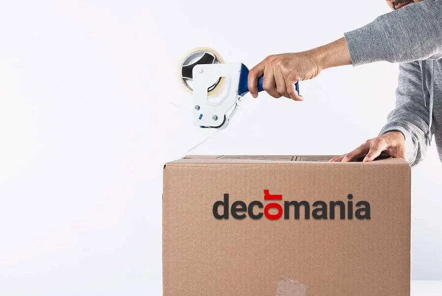 Person sealing a cardboard box with a Decomania logo using a tape dispenser.